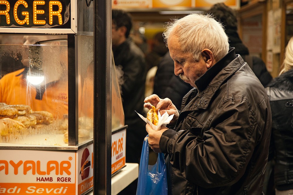 An-old-man-from-Istanbul-eating-his-islak-burger-in-front-of-the-Bambi-Cafe